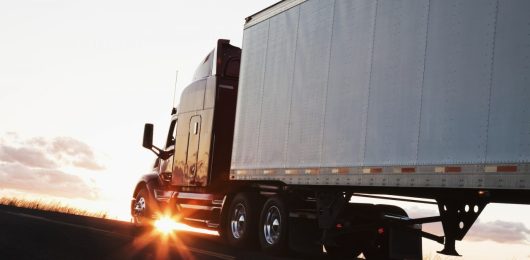 silhouette-of-a-commercial-truck-driving-on-a-highway-at-sunset-.jpg